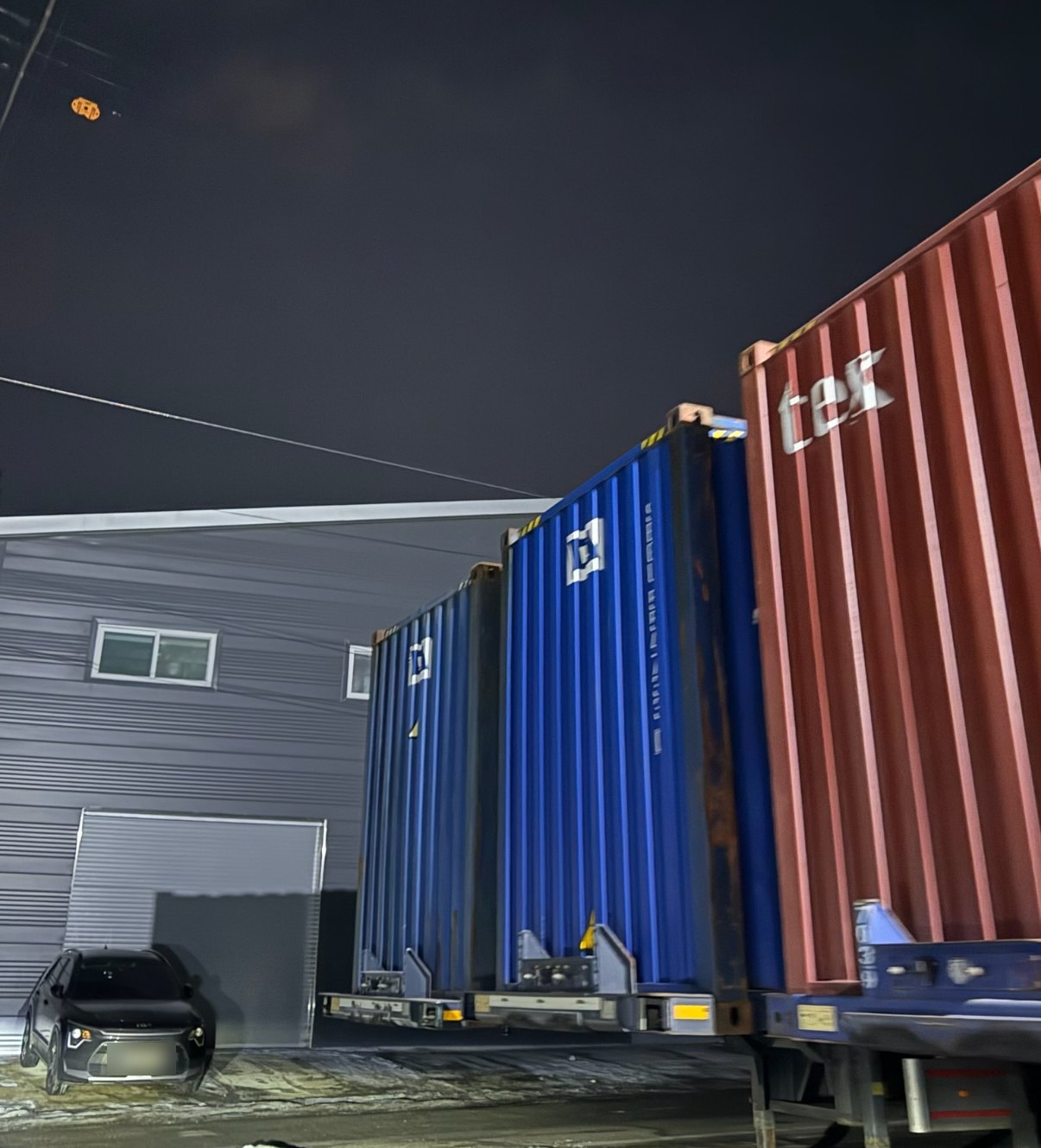Shipping containers loaded on trailers outside a warehouse in South Korea at night